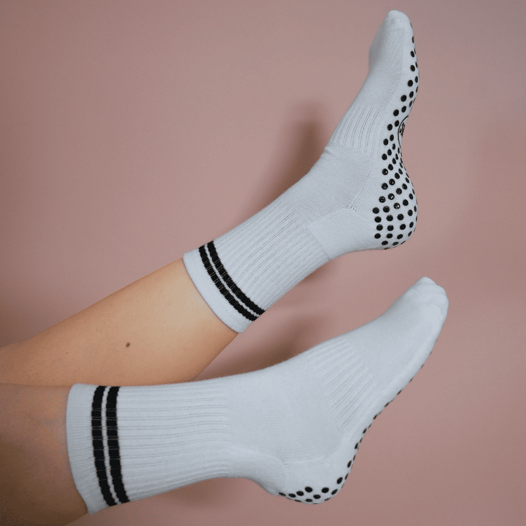 White and black GRIPTEC pilates grip socks worn on the mat