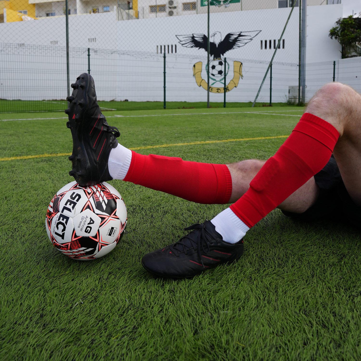 GRIPTEC grip socks worn with red football sock sleeves and shin pad sleeves during football training