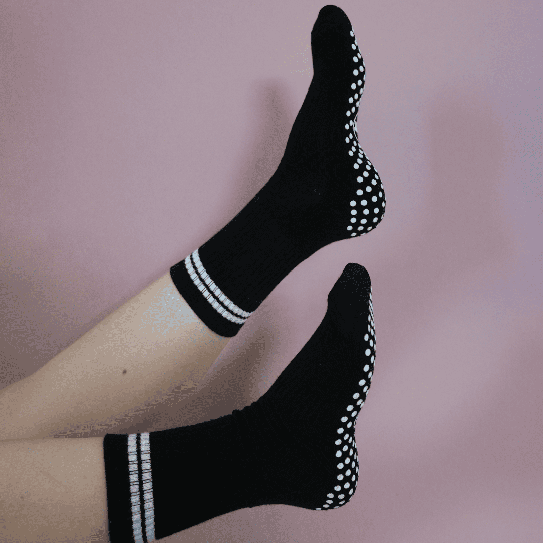 Black and white GRIPTEC pilates grip socks worn on the mat